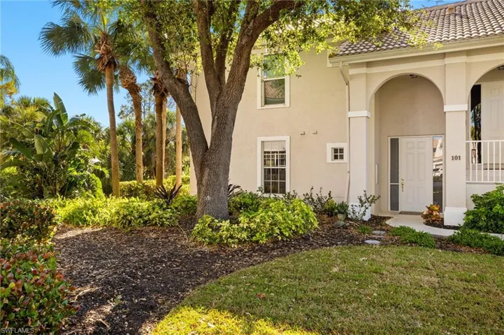 View of exterior entry featuring stucco siding, a tile roof, and a yard