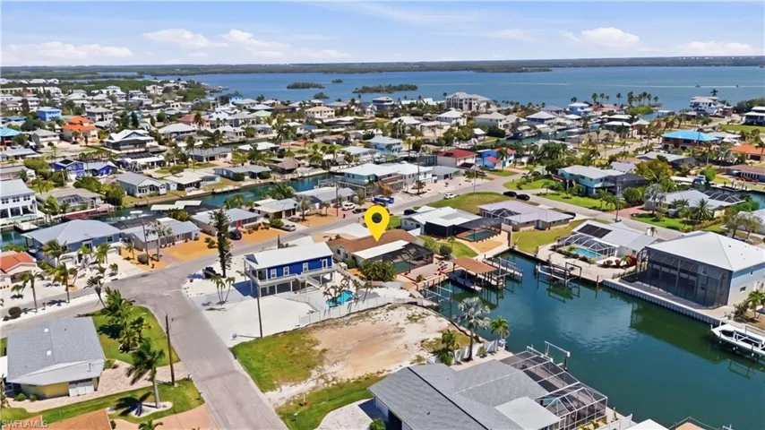 Waterfront property featuring a private boat dock, an elevated residential structure, a swimming pool, and direct canal access - Virtually Edited Image