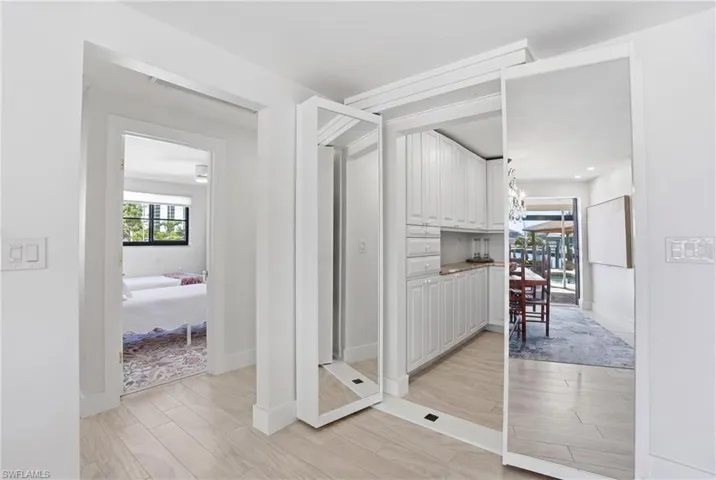 Hallway featuring wood-finish flooring and integrated mirrored panels - Virtually Edited Image
