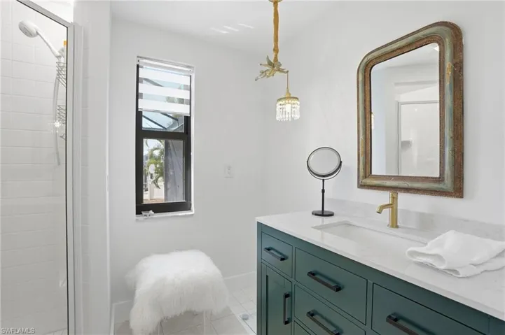 Vanity featuring a white countertop with an integrated sink, gold-finish faucet, and a large framed mirror - Virtually Edited Image