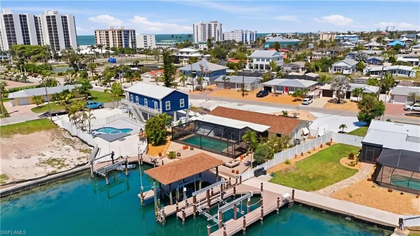 Waterfront property featuring multiple boat docks, a covered boat lift, and an in-ground swimming pool - Virtually Edited Image