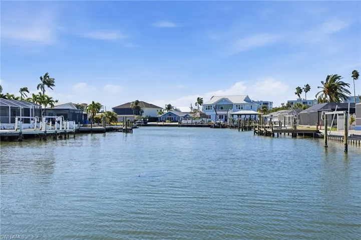 Canal-front property with private dock, surrounded by lush palm trees and waterfront residences - Virtually Edited Image