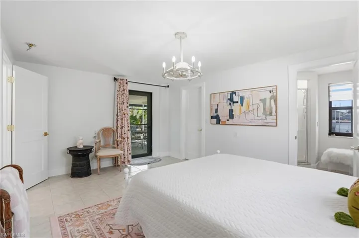 Spacious room with light-toned tile flooring, a contemporary ceiling light fixture, and a glass-paned door opening to an outdoor area - Virtually Edited Image