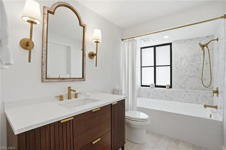 Bathroom featuring a dark wood-finish vanity with a white countertop and gold-tone hardware - Virtually Edited Image