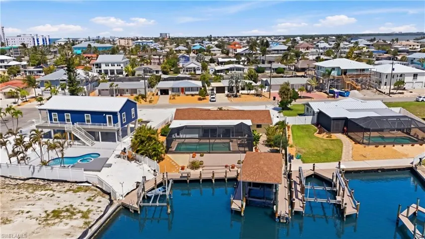 Waterfront property featuring multiple boat slips, a covered boat lift, and a private swimming pool with an integrated spa - Virtually Edited Image