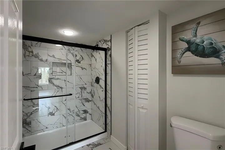 Full bathroom featuring a closet, a marble finish shower, and marble look tiles