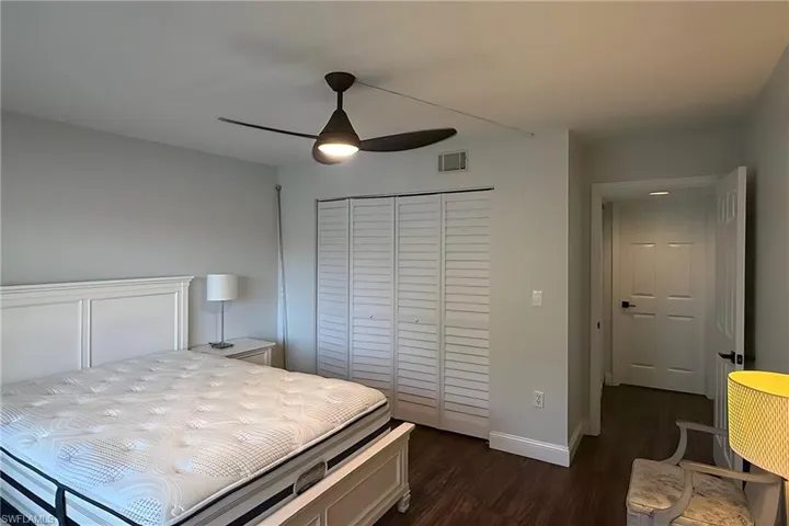 Bedroom featuring dark wood-style flooring, a closet, and a ceiling fan