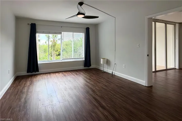 Empty room with dark wood-type flooring and ceiling fan