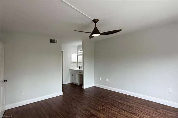 Unfurnished room featuring dark wood-type flooring and ceiling fan