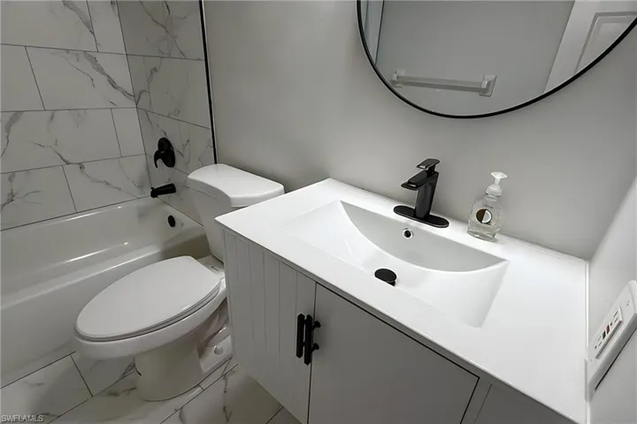 Bathroom featuring light marble finish floors, vanity, and bathtub / shower combination