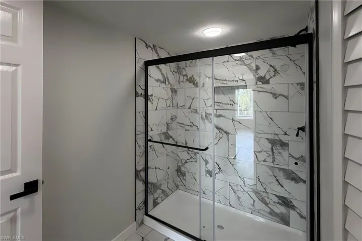 Full bath with a marble finish shower