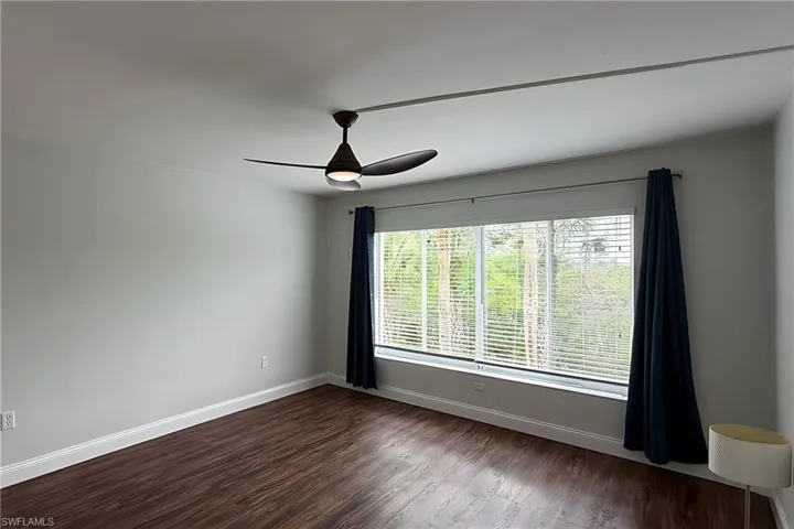 Empty room with dark wood-style flooring and ceiling fan