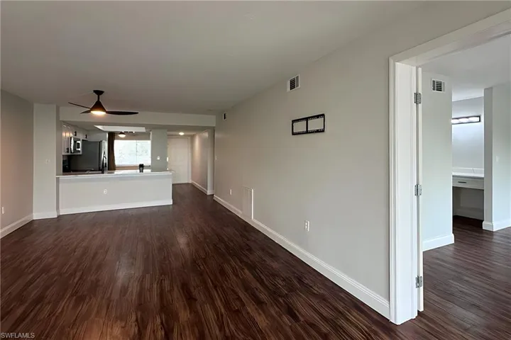Unfurnished living room with dark wood finished floors and a ceiling fan