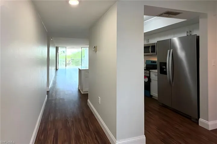 Hall with dark wood finished floors and crown molding