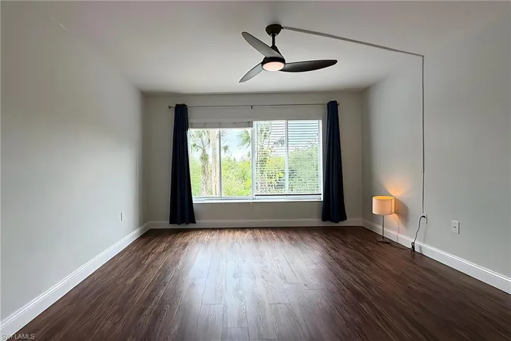 Unfurnished room with dark wood finished floors and a ceiling fan