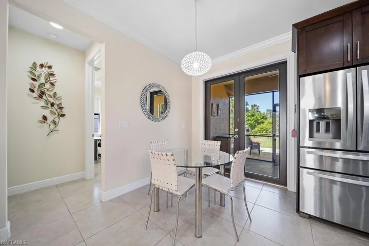 Dining space with crown molding, light tile patterned floors, and french doors