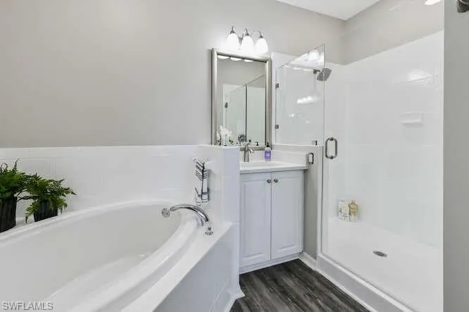 Full bath with a bath, vanity, a shower stall, and dark wood-style floors