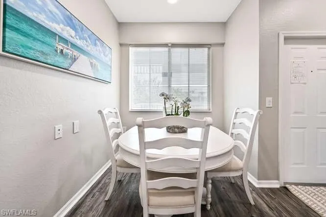 Dining area featuring dark wood-style flooring and a textured wall