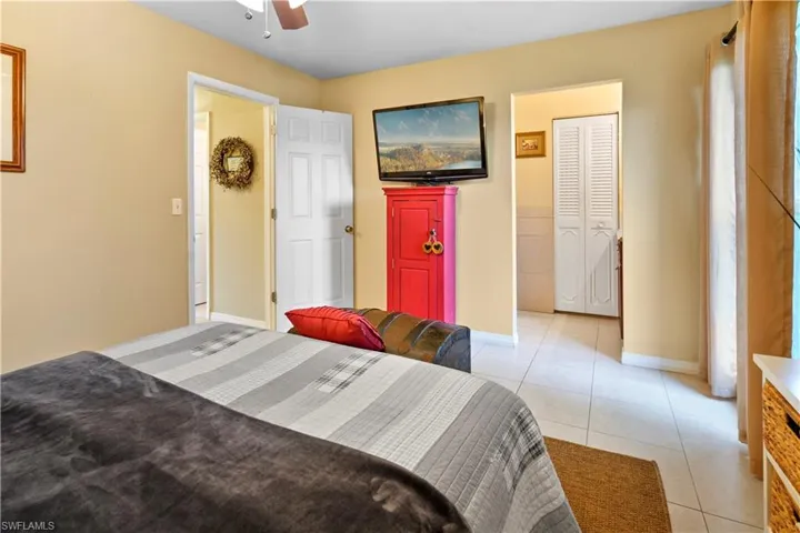 Tiled bedroom featuring ceiling fan, closet and private bathroom.