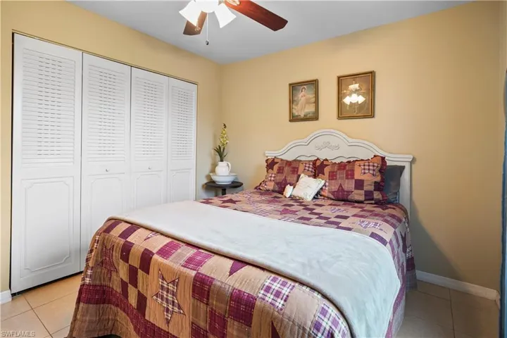 Tiled bedroom featuring ceiling fan and a closet