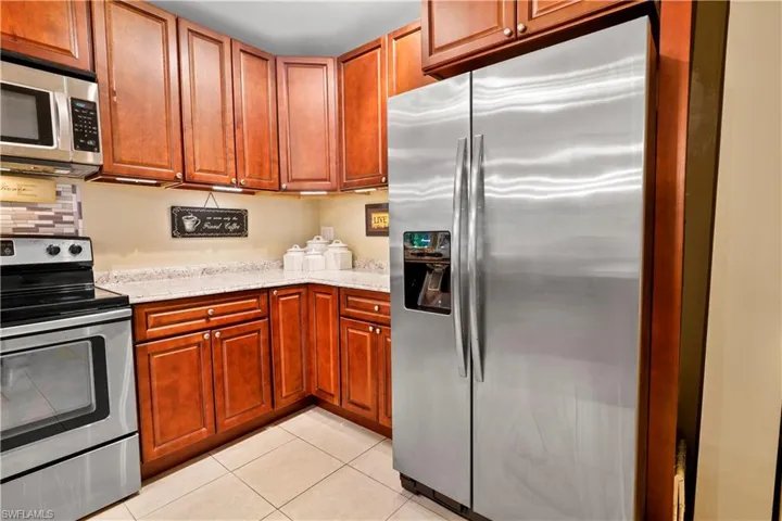 Kitchen featuring light stone like counters, appliances with stainless steel finishes, and light tile patterned floors