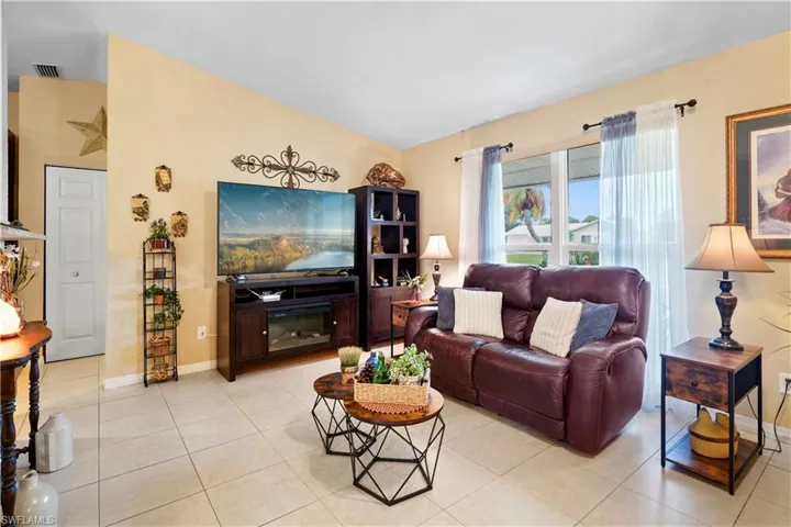 Living room featuring light tile patterned tile flooring and vaulted ceiling.