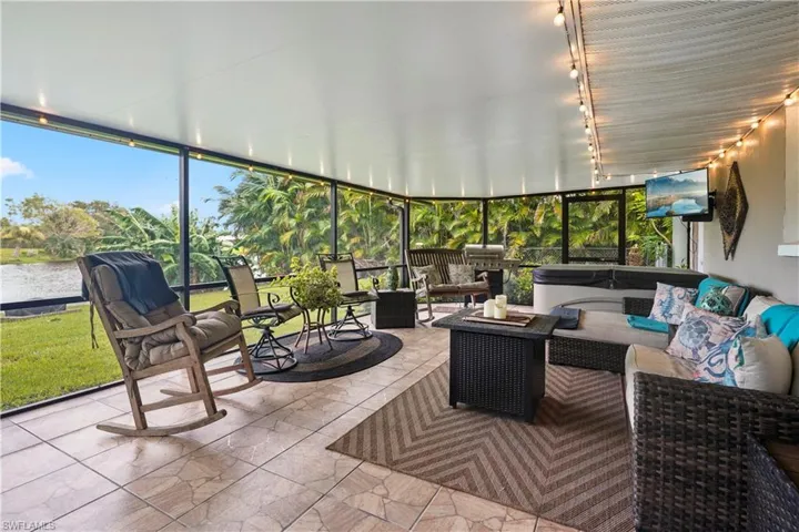 Screened lanai / covered screen porch featuring TV, nice lighting and a fabulous lake view! over looks a very private back yard.