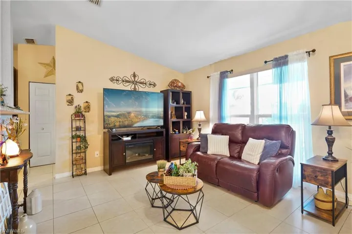 Living room featuring light tile patterned flooring and vaulted ceiling. Great natural lighting.