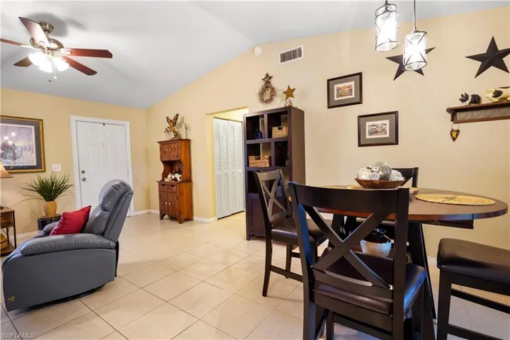 Dining room with lofted ceiling, light tile patterned floors, and vaulted ceiling fan