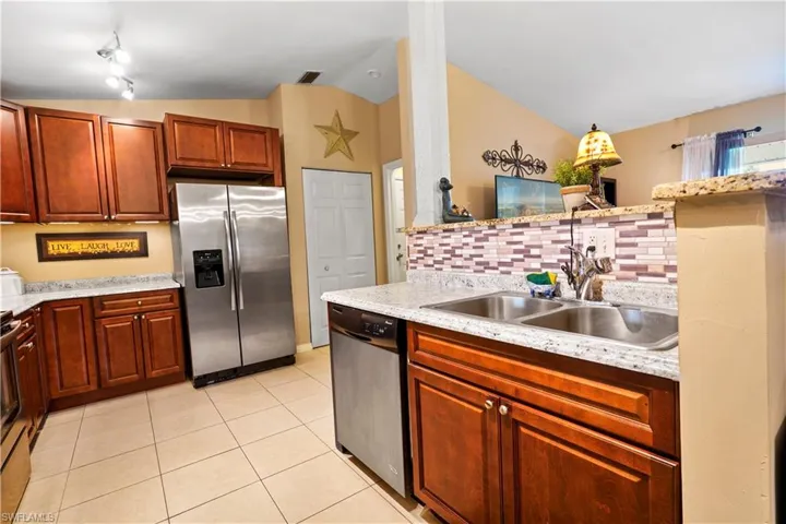 Kitchen with tasteful backsplash, light tile patterned floors, stainless steel appliances, track lighting, and sink