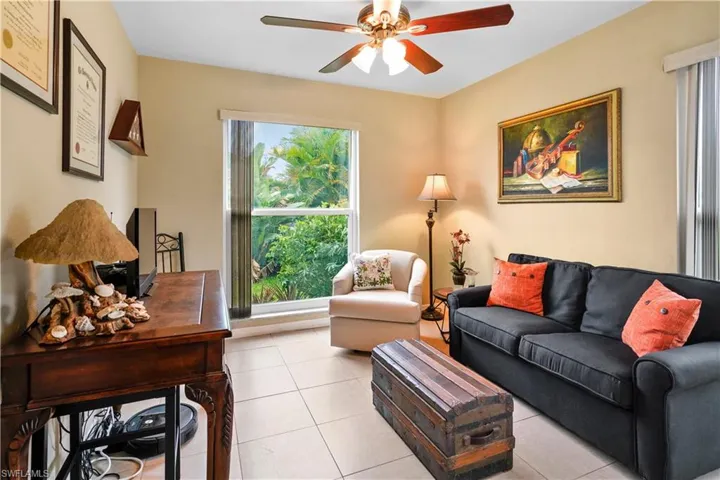 A guest bedroom has been used as a cozy den. Tiled floor and ceiling fan.