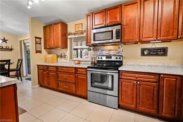 Kitchen featuring track lighting, light stone countertops, stainless steel appliances, and light tile patterned floors