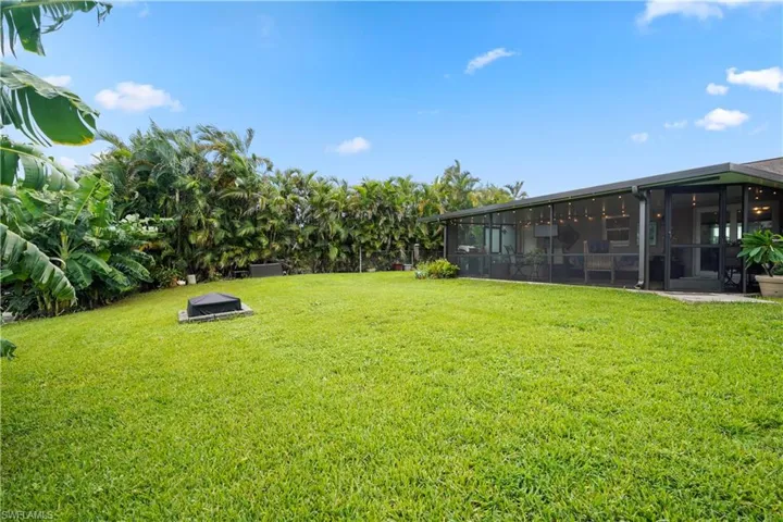 View of yard with a sunroom and firepit.