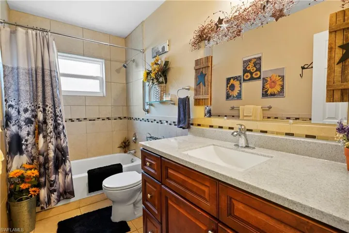 Full guest bathroom with shower / tub combo combo. Large  vanity with nice storage space, tile patterned floors.
