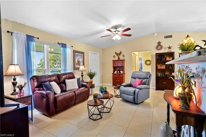 Living room featuring light tile patterned flooring, vaulted ceiling, and ceiling fan