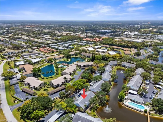 Aerial perspective showcasing a community with multiple residential buildings, surrounded by mature trees and lush landscaping