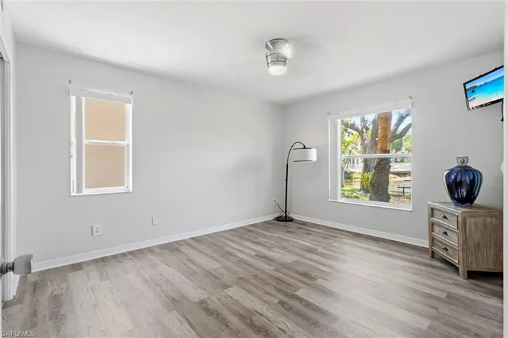Spacious interior room featuring wood-finish flooring, light gray wall paint, and white trim
