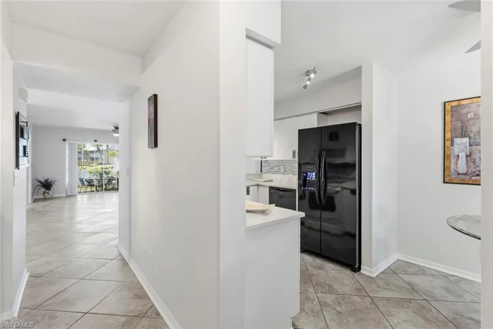 Kitchen featuring a black refrigerator, white cabinetry, track lighting, and a light-toned countertop