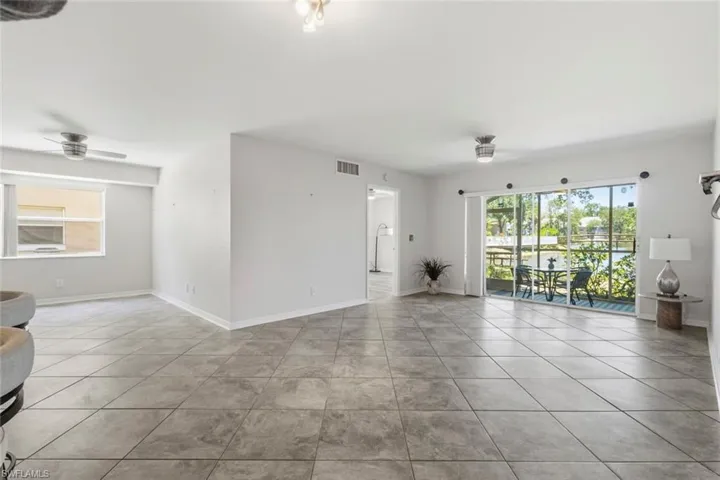 Spacious open-concept living area featuring large format tile flooring and white painted walls