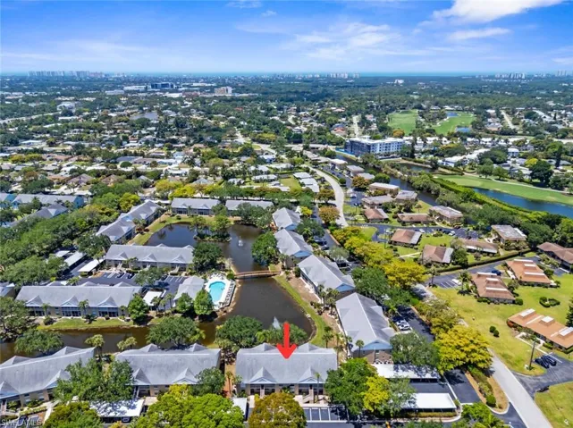 Aerial perspective showcasing a residential community with abundant mature trees, multiple water features, and a community pool