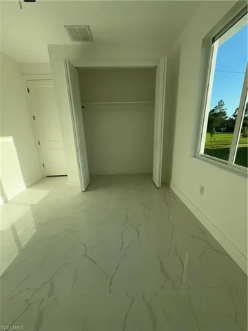 Unfurnished bedroom featuring a closet, tile floors, and multiple windows
