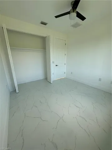Unfurnished bedroom with tile flooring, ceiling fan, and a closet
