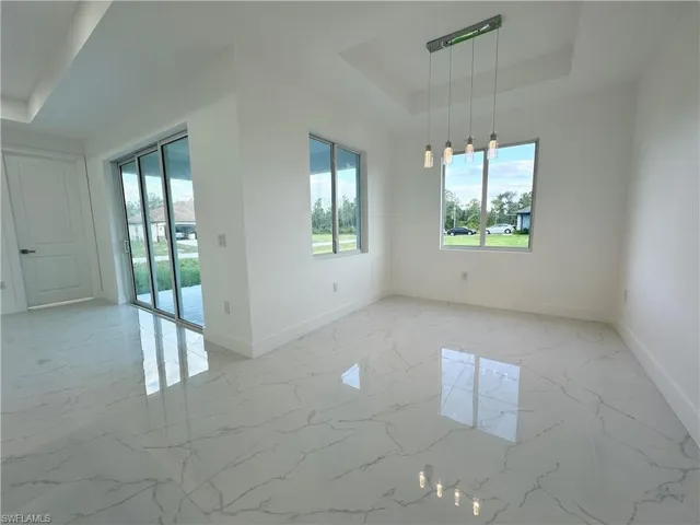 Empty room featuring a tray ceiling and light tile floors