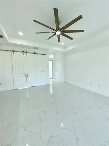 Tiled spare room featuring ceiling fan and a raised ceiling