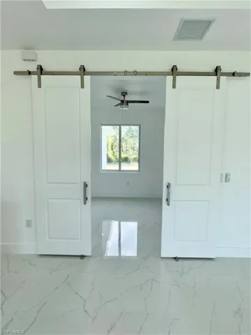 Tiled spare room with a barn door and ceiling fan