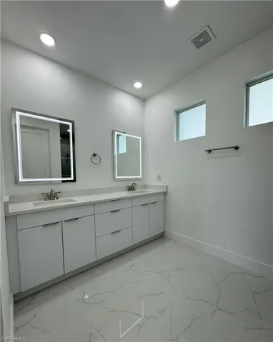 Bathroom featuring tile floors, a healthy amount of sunlight, and double sink vanity
