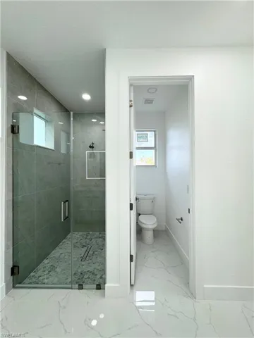 Bathroom with tile flooring, an enclosed shower, and toilet