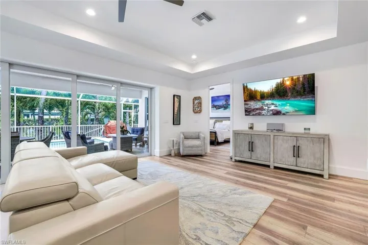 Living room featuring a tray ceiling, light wood-type flooring, and ceiling fan