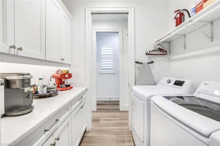 Clothes washing area featuring light hardwood / wood-style flooring, washer and dryer, and cabinets