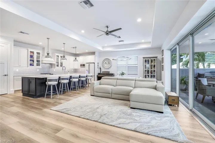 Living room with plenty of natural light, ceiling fan, a tray ceiling, and light hardwood / wood-style floors